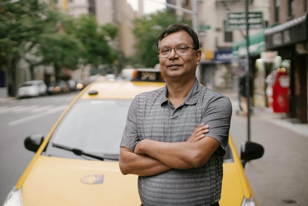 Yellow taxi driver leaning against his taxi in nyc